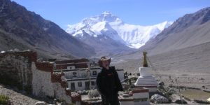 Visitor poses in front of Mt Everest and Rombuk Monastery in Tibet © Mads Mathiasen